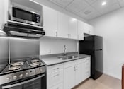 Thumbnail 19 of 61 - A modern kitchen with a stove, microwave, and refrigerator.