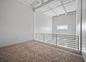 Thumbnail 23 of 58 - A room with a carpeted floor and a window with a metal railing.