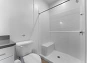 Thumbnail 29 of 61 - A white toilet sits next to a white bathtub in a bathroom.