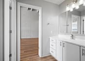 Thumbnail 14 of 58 - A bathroom with a white sink, mirror, and cabinets.