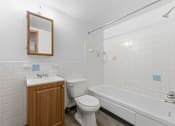 Thumbnail 11 of 12 - A white bathroom with a toilet, sink, and bathtub.