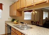 Thumbnail 2 of 13 - A kitchen with wooden cabinets and a marble countertop.