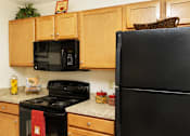 Thumbnail 4 of 13 - A black refrigerator sits next to a black stove in a kitchen.