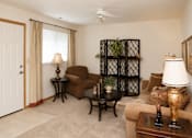Thumbnail 7 of 13 - A living room with a brown couch, a black coffee table, and a white ceiling fan.