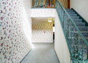 Thumbnail 24 of 31 - a staircase with a glass railing and a wall with floral wallpaper