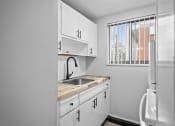 Thumbnail 23 of 35 - an empty kitchen with white cabinets and a window