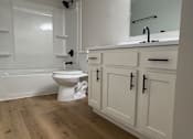 Thumbnail 9 of 18 - A white bathroom with a wooden floor and a white toilet.