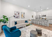 Thumbnail 6 of 58 - A blue armchair sits in a living room with a white couch and a rug. at The Lumos Apartments, Cleveland, Ohio