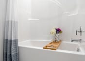Thumbnail 15 of 58 - A white bathtub with a wooden tray holding a vase of flowers. at The Lumos Apartments, Cleveland, Ohio