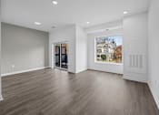 Thumbnail 24 of 58 - A room with wooden flooring and a large window showing a house. at The Lumos Apartments, Ohio, 44106