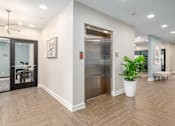 Thumbnail 36 of 44 - A modern office hallway with a wooden floor, a glass door, a potted plant, and a bench. at Park Lamont Townhomes Apartments, Cleveland, Ohio