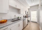 Thumbnail 2 of 44 - A modern kitchen with white cabinets and a granite countertop. at Park Lamont Townhomes Apartments, Cleveland, Ohio