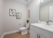 Thumbnail 7 of 44 - A white toilet sits next to a white sink in a small bathroom. at Park Lamont Townhomes Apartments, Cleveland, Ohio