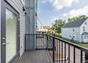 Thumbnail 8 of 44 - A balcony with a black railing and a door with a window. at Park Lamont Townhomes Apartments, Ohio, 44106