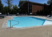 Thumbnail 32 of 56 - a swimming pool with chairs around it in front of a building at Heritage Apartments, Columbus, 43212