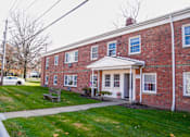 Thumbnail 19 of 20 - the front of a brick building with a sidewalk and grass