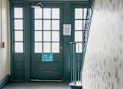 Thumbnail 16 of 20 - a hallway with stairs and a green door and windows