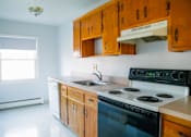 Thumbnail 1 of 20 - a kitchen with a stove and a sink and wooden cabinets