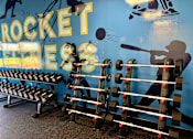 Thumbnail 18 of 19 - A gym wall with a rocket and a man lifting weights. at Vivo Toledo Apartments, Toledo, Ohio
