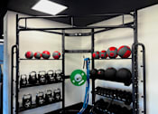 Thumbnail 17 of 19 - A rack of red and black kettlebells and weight plates in a gym. at Vivo Toledo Apartments, Ohio, 43607