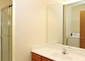 Thumbnail 13 of 15 - A bathroom with a sink, mirror, and shower.