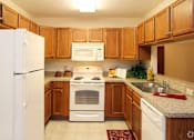Thumbnail 2 of 15 - A kitchen with wooden cabinets and white appliances.