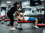 Thumbnail 27 of 35 - a man laying on a bench in a gym with a woman holding a dumbbell at Market Square Place, Pennsylvania