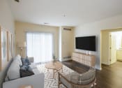 Thumbnail 3 of 26 - a living room with a couch and a table and a television at Highlands at Faxon Woods, Quincy, MA