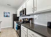 Thumbnail 3 of 27 - A Kitchen with Black Appliances at Flats on Chapel Apartments, Waco, 76712