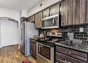 Thumbnail 2 of 27 - a kitchen with stainless steel appliances and wooden cabinets at Altezza High Desert, Albuquerque