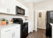Thumbnail 4 of 14 - a kitchen with white cabinets and black appliances and a black refrigerator at Canyon Creek, Austin, TX