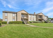 Thumbnail 20 of 23 - A large apartment complex with a green lawn in front.