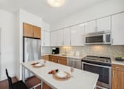 Thumbnail 2 of 34 - a kitchen with stainless steel appliances and a white table at The Merc, Waltham, MA, 02453