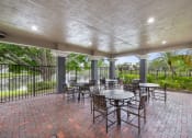 Thumbnail 17 of 21 - a covered patio with tables and chairs and a fence at Gateway Club, Boynton Beach, Florida