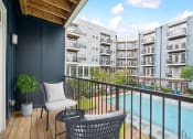 Thumbnail 7 of 22 - a balcony with chairs and a pool and an apartment building at Glenwood at Grant Park Apartments, Georgia