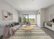 Thumbnail 2 of 23 - an open living room with a gray couch, a coffee table, and large windows at the Residences at Manchester Place in Manchester, New Hampshire