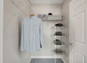 Thumbnail 5 of 23 - a walk in closet with a shirt hanging on a rack and shelf at the Residences at Manchester Place in Manchester, New Hampshire