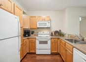 Thumbnail 6 of 23 - a kitchen with wooden cabinets and a white stove and refrigerator at the Residences at Manchester Place in Manchester, New Hampshire