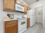 Thumbnail 3 of 31 - a kitchen with white appliances and wooden cabinets at Grandeville on Saxon, Florida