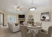 Thumbnail 7 of 23 - a living room with a table and chairs and a fireplace