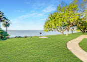 Thumbnail 15 of 18 - A green lawn with a pathway and a signpost at The Bay Club, Corpus Christi, TX, Texas, 78418