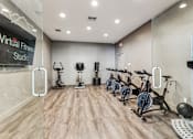 Thumbnail 12 of 27 - a fitness room with cardio bikes and weights on a wooden floor at Altezza High Desert, Albuquerque
