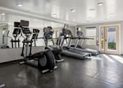 Thumbnail 9 of 23 - A gym with treadmills and elliptical machines.