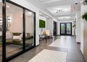 Thumbnail 22 of 33 - a hallway with glass doors and a living room with a couch at Edgebrook Residences, Merrimack, 03054