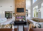 Thumbnail 19 of 33 - a clubroom with two couches, a coffee table, a fireplace, and a TV at Edgebrook Residences, Merrimack, 03054