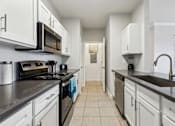 Thumbnail 2 of 27 - A Kitchen with Black Countertops at Flats on Chapel Apartments, Waco