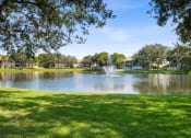 Thumbnail 21 of 21 - a fountain in the center of a lake with grass and trees at Gateway Club, Boynton Beach, 33436