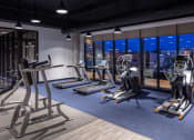 Thumbnail 26 of 40 - a workout room with treadmills and other exercise equipment at night at Maven on Broadway, Rochester, MN, 55904