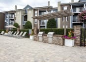 Thumbnail 10 of 14 - a patio with chairs and a pergola in front of an apartment building at Thornberry Apartments, Charlotte, NC 28262