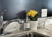 Thumbnail 8 of 12 - a kitchen sink with a vase of yellow flowers next to it at 2300 West Apartments, Reno, NV